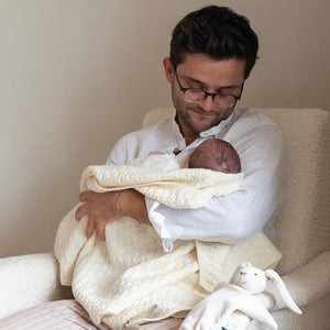 Un bébé s'endort dans les bras de son papa.
