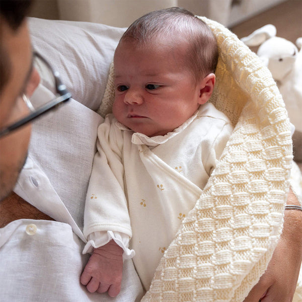 Un bébé enveloppé dans une couverture en laine 100% mérinos fabriquée en France.