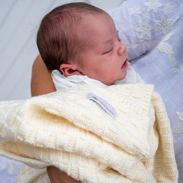 Un bébé endormi, enveloppé dans une couverture en laine mérinos fabriquée en France.