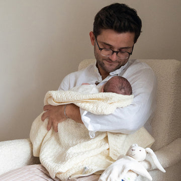 Un bébé s'endort dans les bras de son papa.
