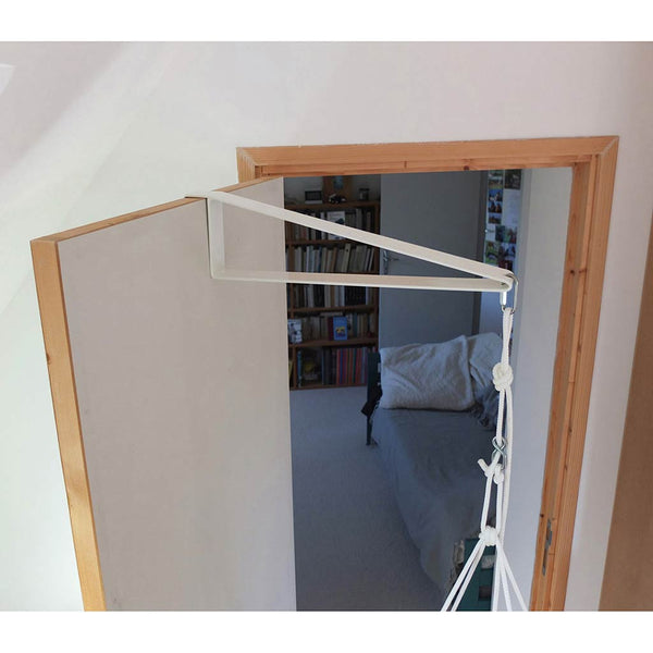 L’équerre de porte se pose sur la porte grâce à une « patte » qui adopte la profil de la porte ; elle a 50cm de portée, le hamac mesure 40cm de large, ce qui laisse donc 10cm entre la porte et le cadre de bois. L’équerre de porte convient au nourrisson, et au tout-petit bébé, de moins de 8 kg, qui ne se balance pas encore vivement ; ce qu’il faut protéger c’est la porte, et pas le bébé, car il est maintenu à l’intérieur du cadre de bois, donc loin de la porte.
